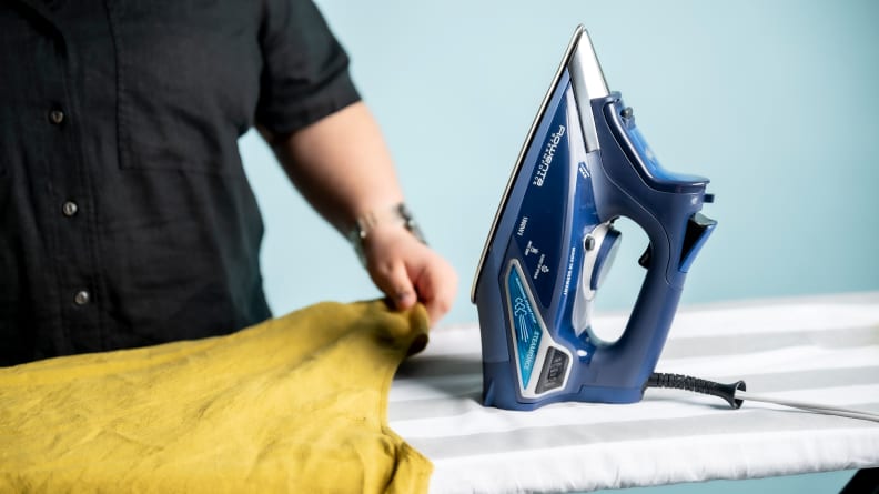 The Rowenta DW9280 resting on an ironing board next to a person with a yellow shirt.