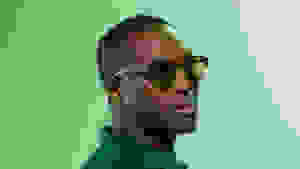 Black man wearing green tinted sunglasses on green background