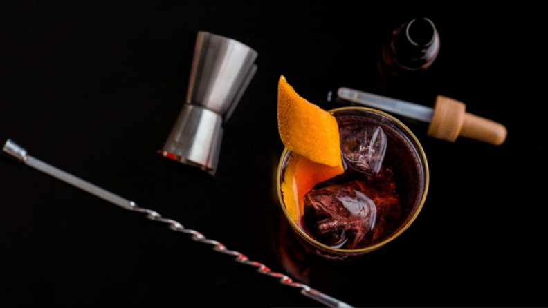 A glass and cocktail gadgets on a black background