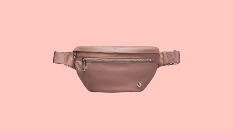 A rose pink lululemon belt bag featuring a bronze logo and zipper on the front.