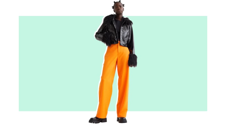 A model wears a faux fur jacket with orange pants.