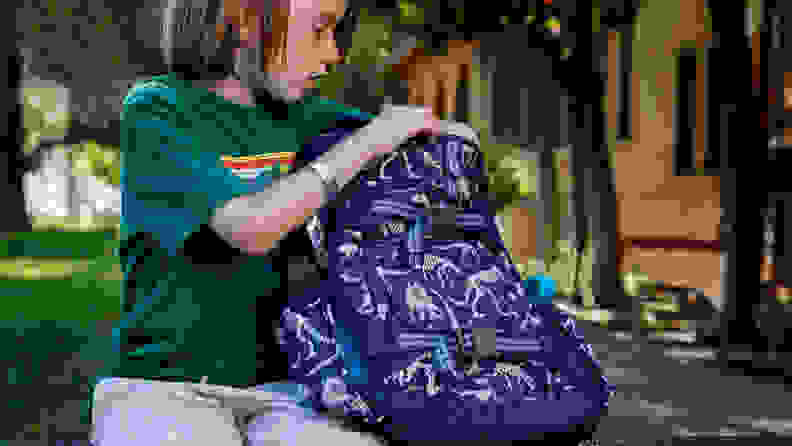 A young boy sitting on a bench putting books in a backpack