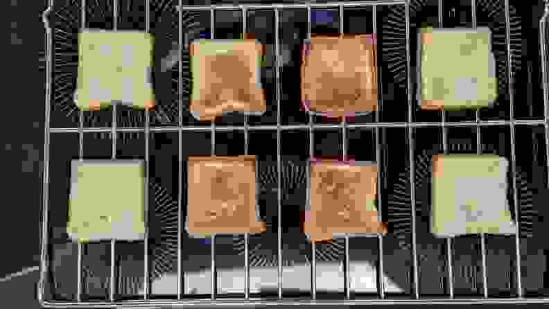 Eight slices of toast on a wire rack that have been toasted to different degrees.