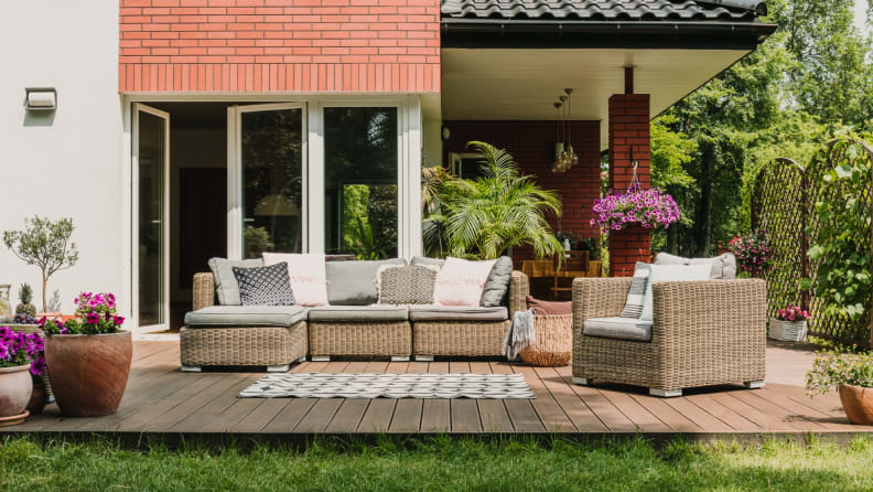Stylish patio furniture set with rug next to backyard lawn