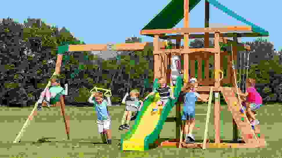 A bunch of kids playing in a backyard outdoor playset.