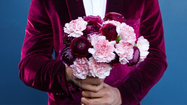 Urban Stems bouquet held by a man in a velvet suit