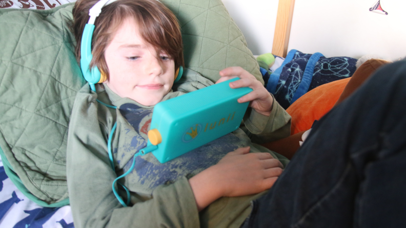 A child listens to a Lunii audio player