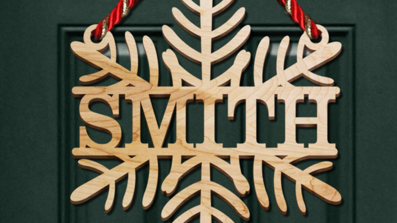 Wooden snowflake door hanger reading 'Smith' on a green door