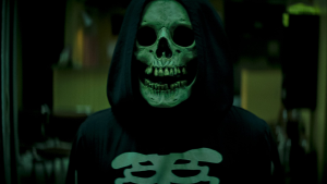 在《恐惧街》(Fear Street)中，一个戴着骷髅面具的杀手在阴凉处制造恐怖。