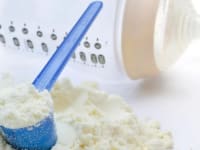 An image of powdered baby formula sitting on a counter near an empty baby bottle.