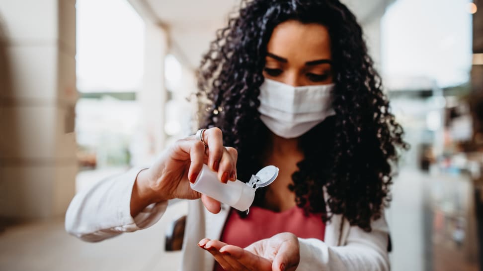 Woman wearing mask pouring hand sanitizer into her hand