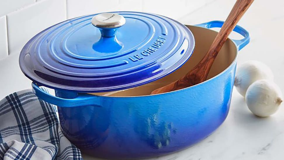A wooden spoon sits in a blue Dutch oven.