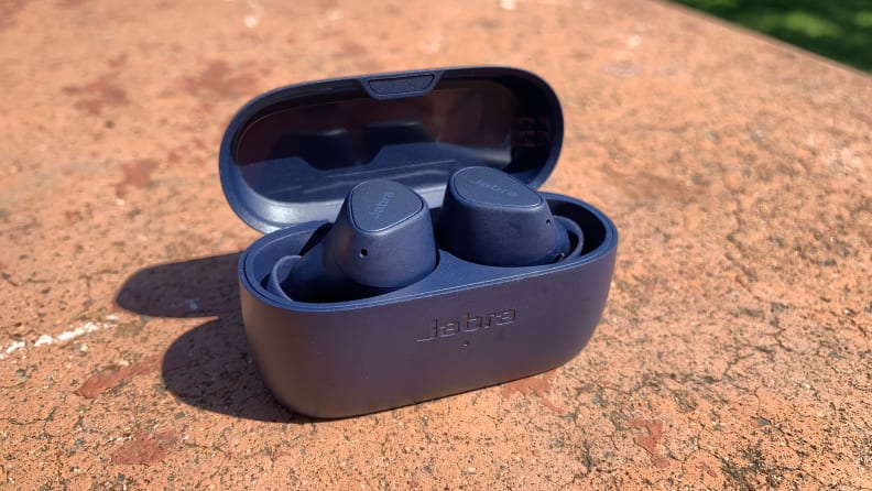 Jabra Elite 4 earphones inside a black case on a rock.