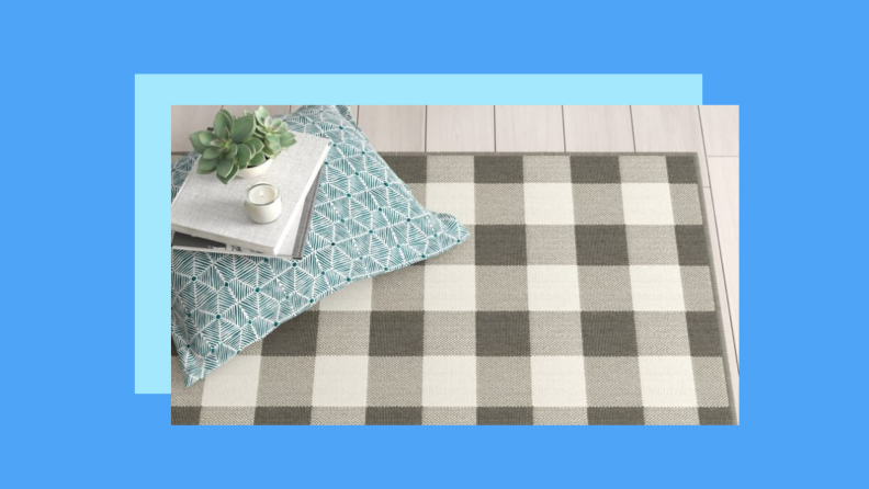 A gingham rug on the floor against a blue background.