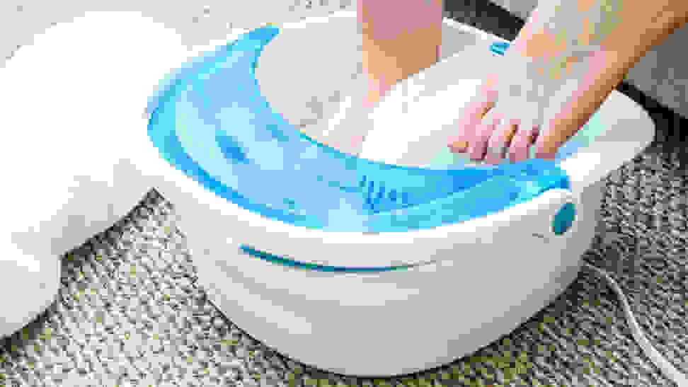 A pair of feet in a white and blue foot spa.