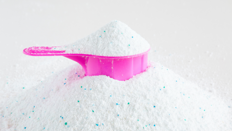 A pink cup is surrounded by powder detergent.