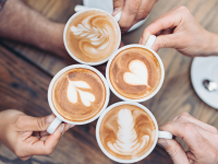 Four people holding cups of cappuccino from above,  displaying cappuccino art