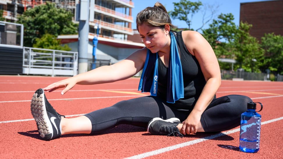 Woman runner stretching on a track