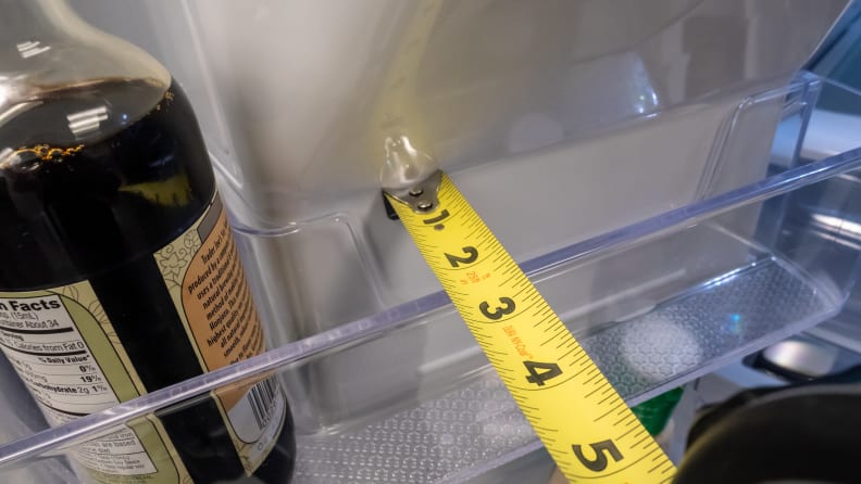 A shot of one of the door bins on a Samsung RF27T5201SG French door refrigerator with a measuring tape stretched across the top.  The measuring tape shows that the bin is only 2.5 .  is about