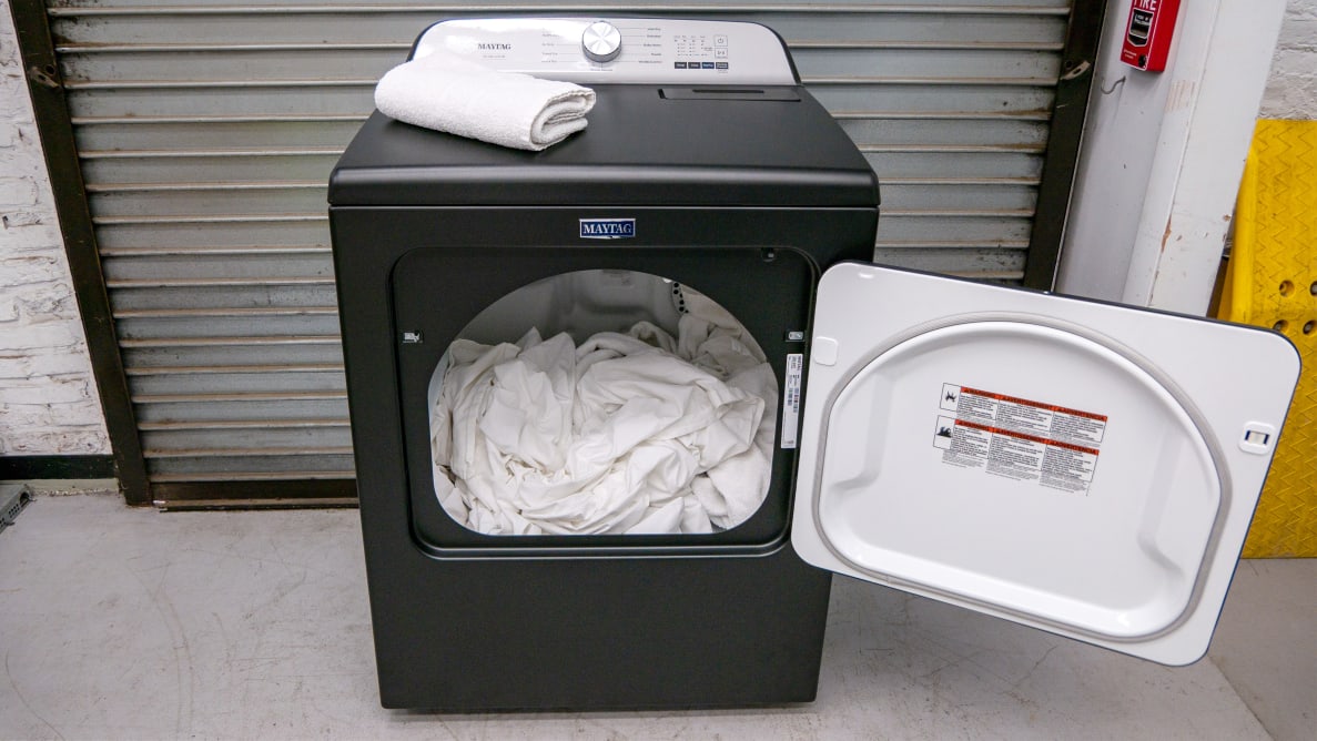 A black Maytag Pet Pro MED6500MBK dryer door open with white towels inside