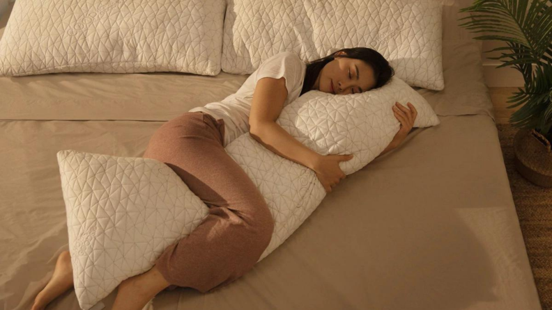 A person cuddled up with a large body pillow.