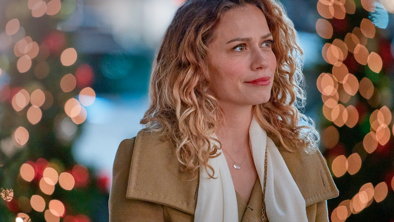 Emily (Bethany Joy Lenz) is gorgeously lit by the red and gold glow of Christmas tree lights in a shot from 2021's made-for-TV movie An Unexpected Christmas.
