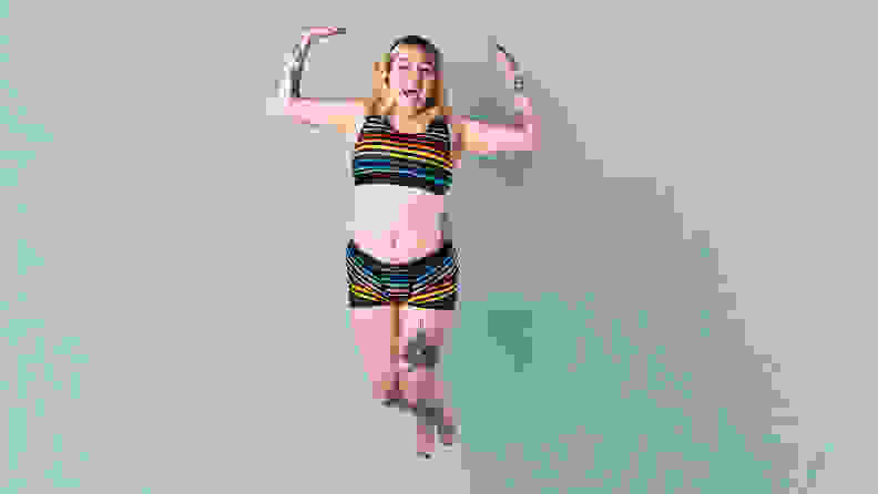 A person jumping up in the air against a blue background in TomboyX underwear.