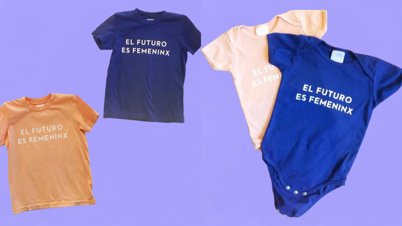 Multi-colored shirts and onesies that read "El future es femininx" in front of purple background.