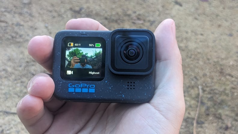 A man pointing the GoPro Hero12 Black at himself as he snaps a picture with his phone.