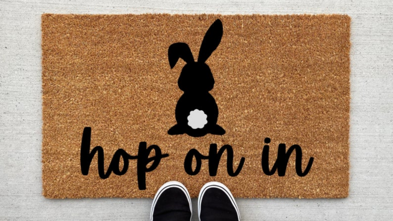 A brown doormat with a black bunny outine