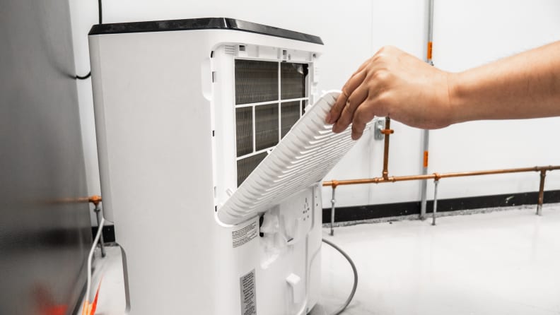 A person slides a filter into a dehumidifier during lab testing of the best dehumidifiers.