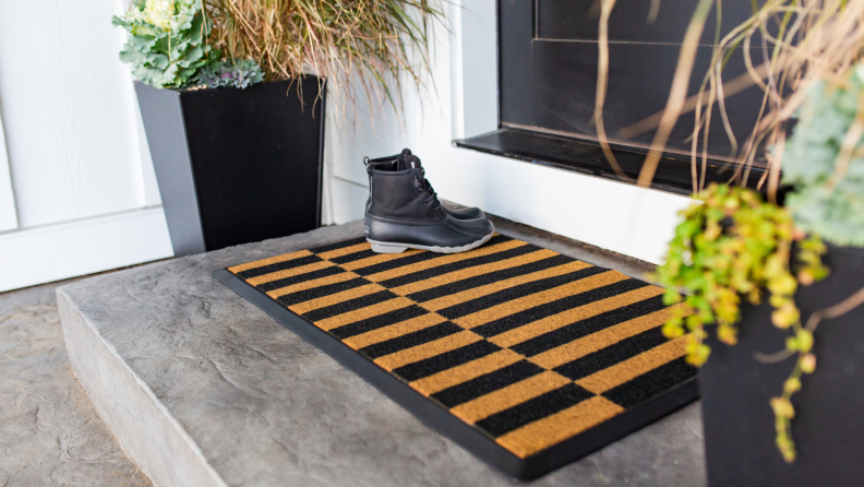 A pair of boots sits on a Ruggable welcome mat.