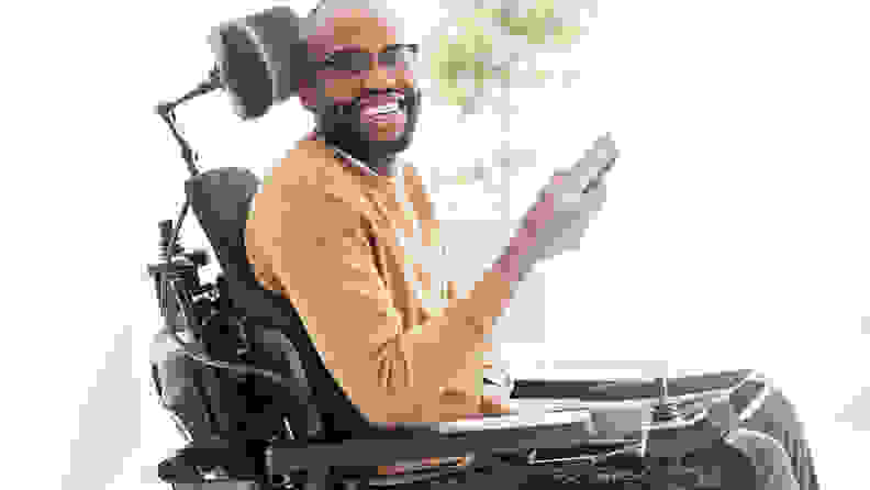 An African American man sitting in a wheelchair, holding a smartphone.