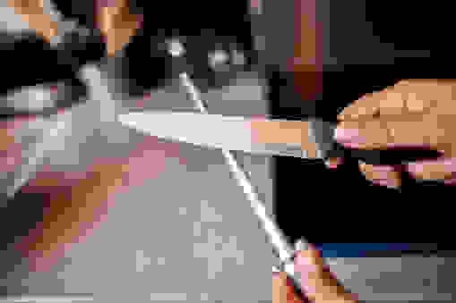Cette photographie montre une personne en train d'aiguiser un couteau Ã  l'aide d'un fusil, d'une lime.