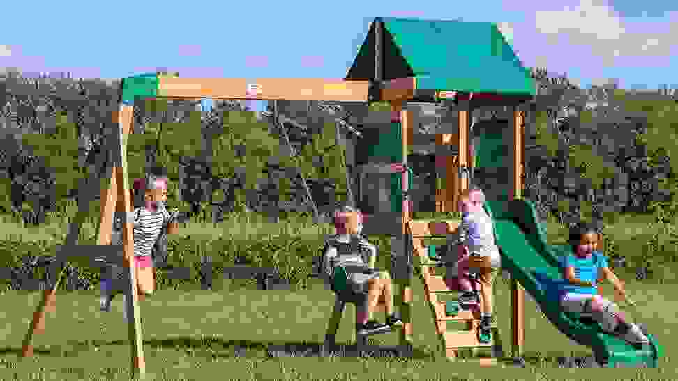 A group of kids playing on a backyard swing set.