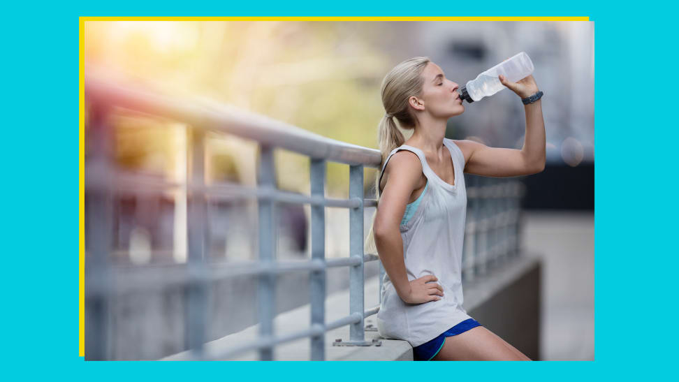 Person resting on rail, drinking from reusable water bottle outdoors.