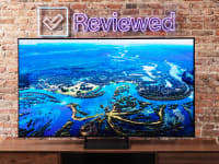 The Samsung S90C QD-OLED TV on an entertainment center with a brick background.