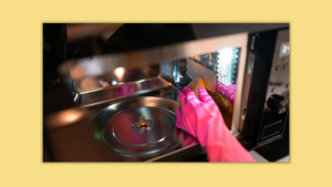 A pink glove cleaning the inside of a microwave