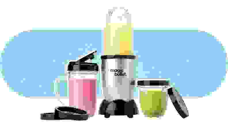 The Magic Bullet Blender in the middle of two included cups and their lids, with smoothies inside.