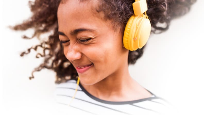 Child smiling while wearing yellow headphones.