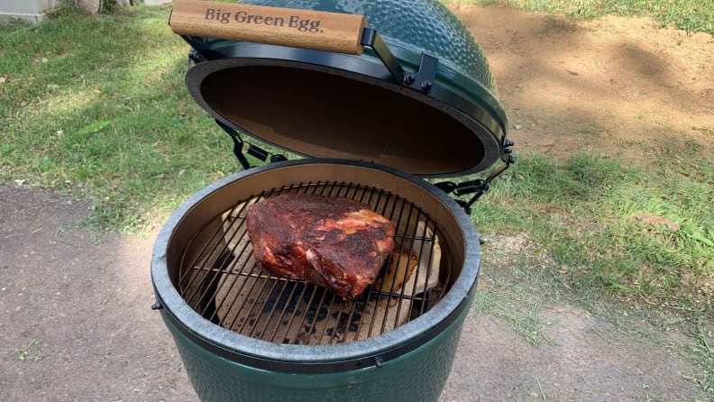 An open Big Green Egg, revealing a cooked brisket inside.