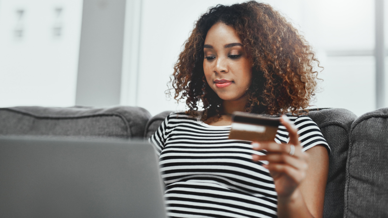 A woman sits in front of her computer with her credit card, researching extended warranty information.