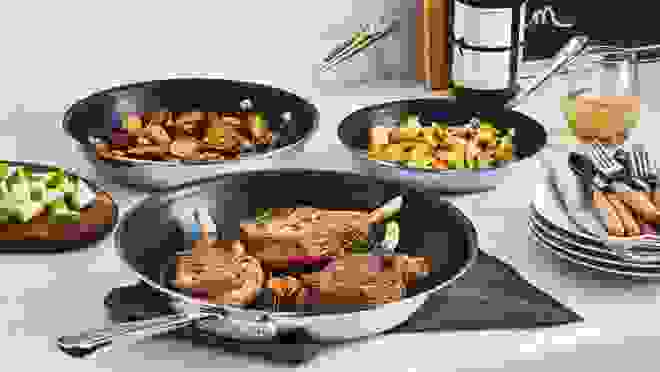 Three pans on a stove cooking various food items