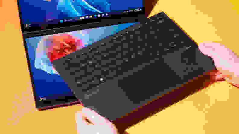 Person placing interchangeable keyboard on top of touchscreen of the 2024 Asus Zenbook Duo.