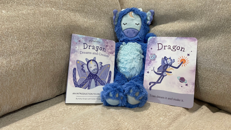 Slumberkins Dragon Kin stuffed animal next to included affirmation card and book.