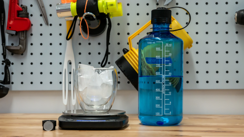 A temperature sensor, cup of ice, and water bottle on a workbench