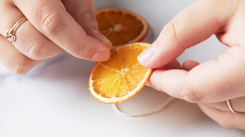 A needle being threaded through a dried orange slice.