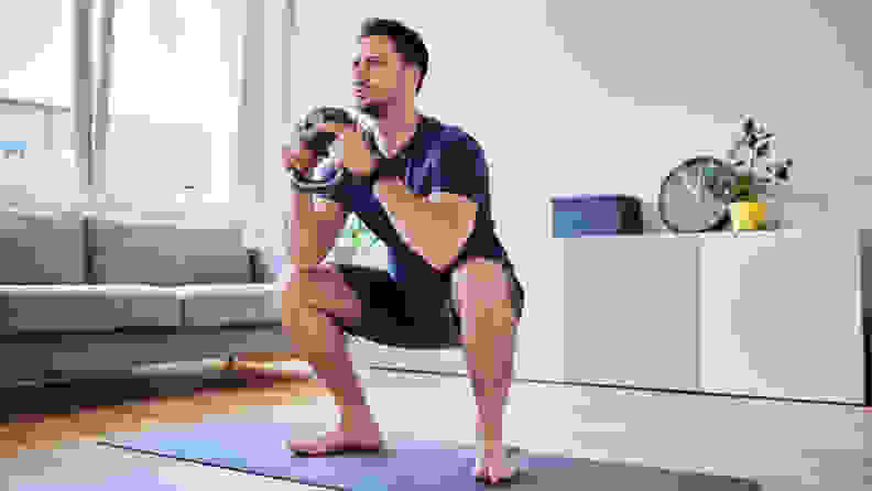 A man doing a squat with a kettlebell.