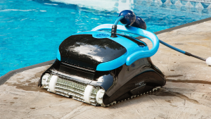 Close-up of a black and blue Dolphin Nautilus CC Plus Wi-Fi robotic pool cleaner at the edge of an outdoor swimming pool.