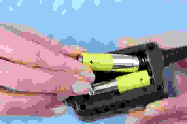 Female hands inserting batteries into remote closeup. Repair of household appliances concept